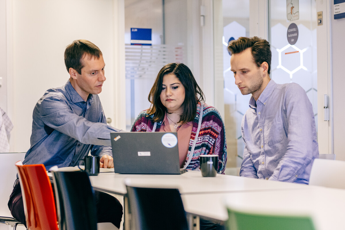 Three researchers discussing their work on a computer screen
